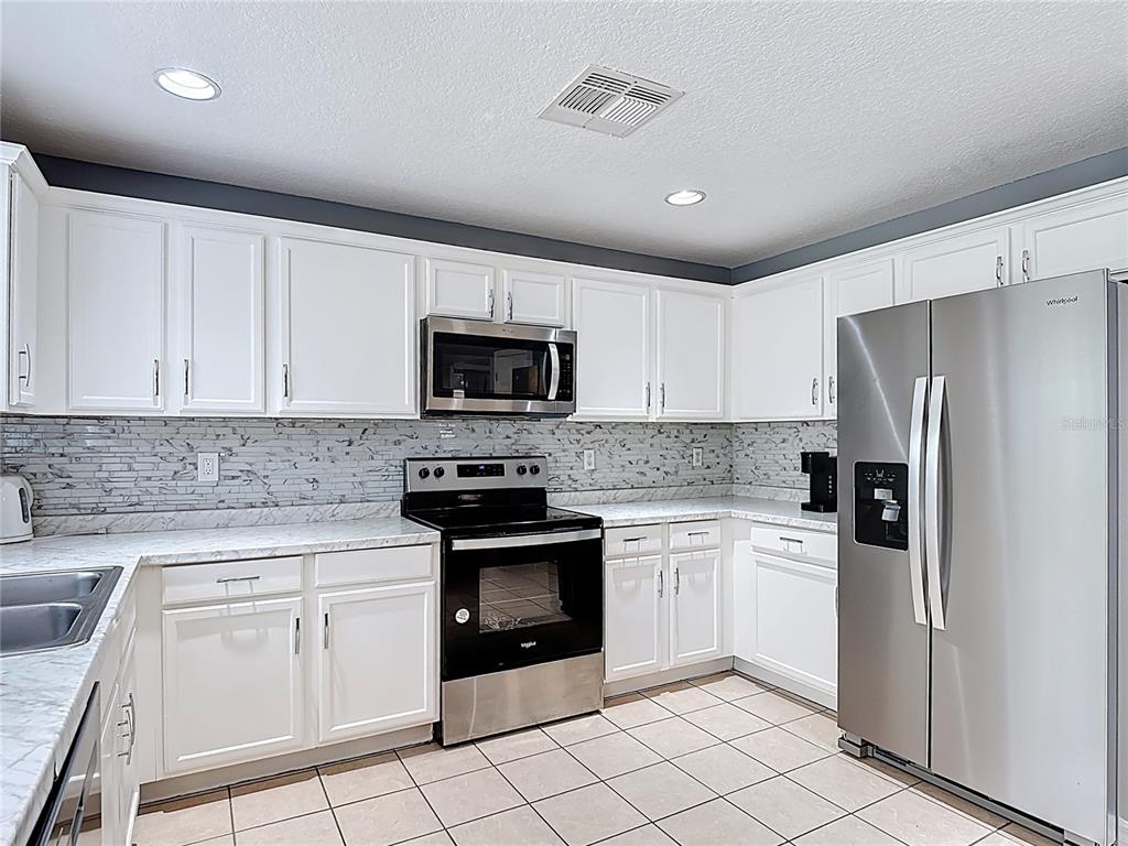320 Mockingbird Road Davenport, FL 33896 - Photo 7 of 34 a kitchen with white cabinets stainless steel appliances and sink