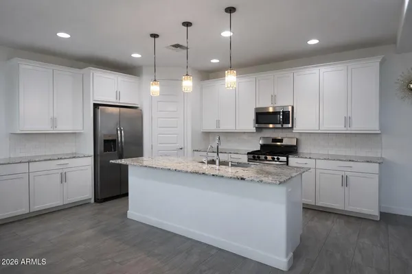 a kitchen with stainless steel appliances granite countertop a sink a stove a refrigerator and cabinets
