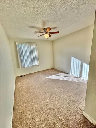 an empty room with windows and fan