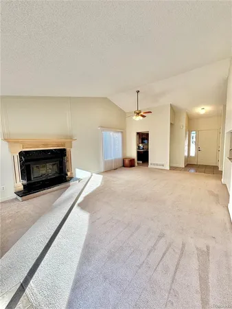 a view of a livingroom with a fireplace a chandelier and windows