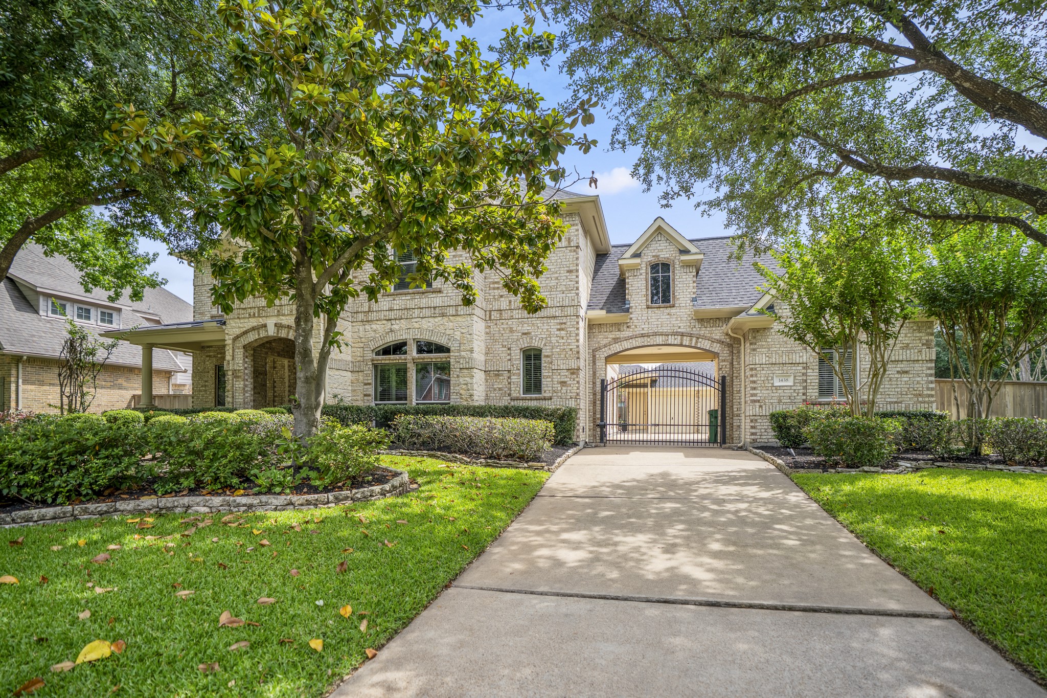 1438 Hatchmere Place Spring, TX 77379 - Photo 2 of 50 Exceptional curb appeal with mature shade trees that frame the walkway of the home, with mature landscaping, a beautiful front elevation & private driveway gate & porte-cochère.