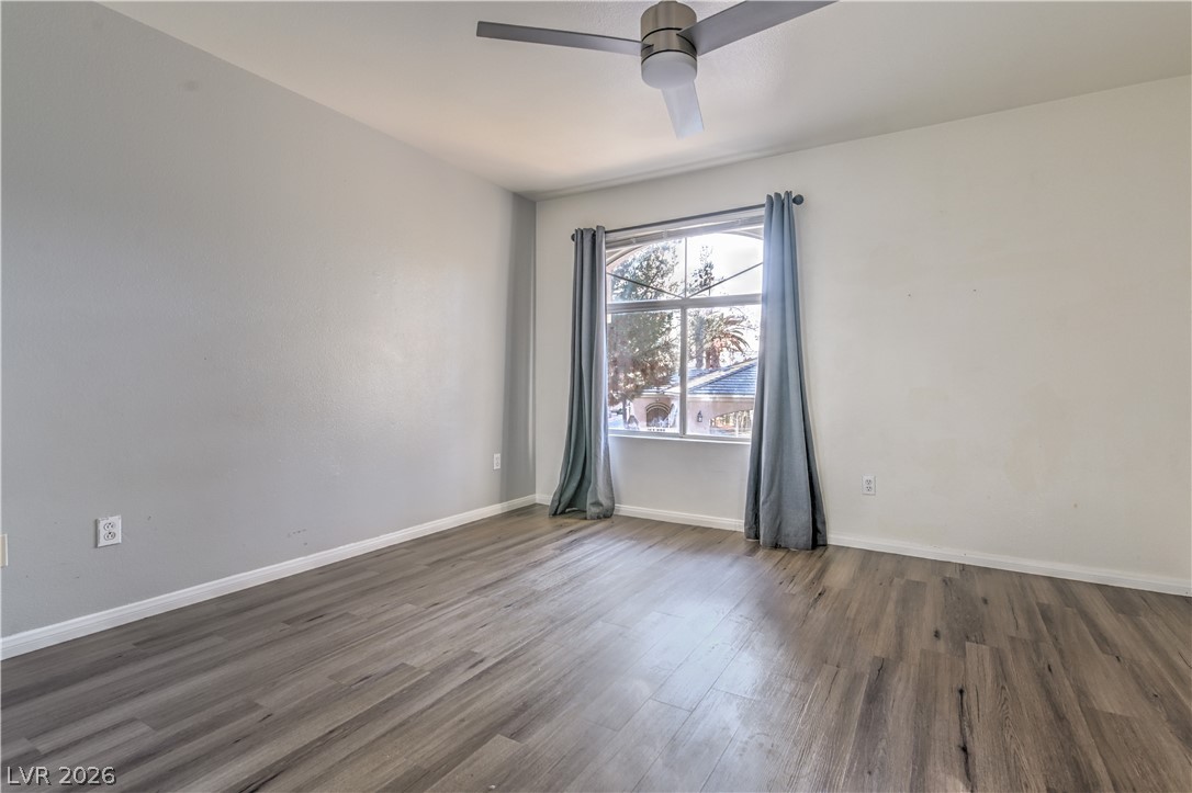 3950 South Sandhill Road, Unit 112 Las Vegas, NV 89121 - Photo 14 of 33 Empty room with wood finished floors, baseboards, and ceiling fan