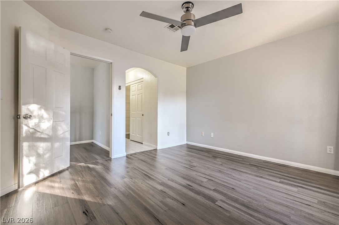 3950 South Sandhill Road, Unit 112 Las Vegas, NV 89121 - Photo 15 of 33 Spare room with a ceiling fan, dark wood-style floors, baseboards, visible vents, and arched walkways