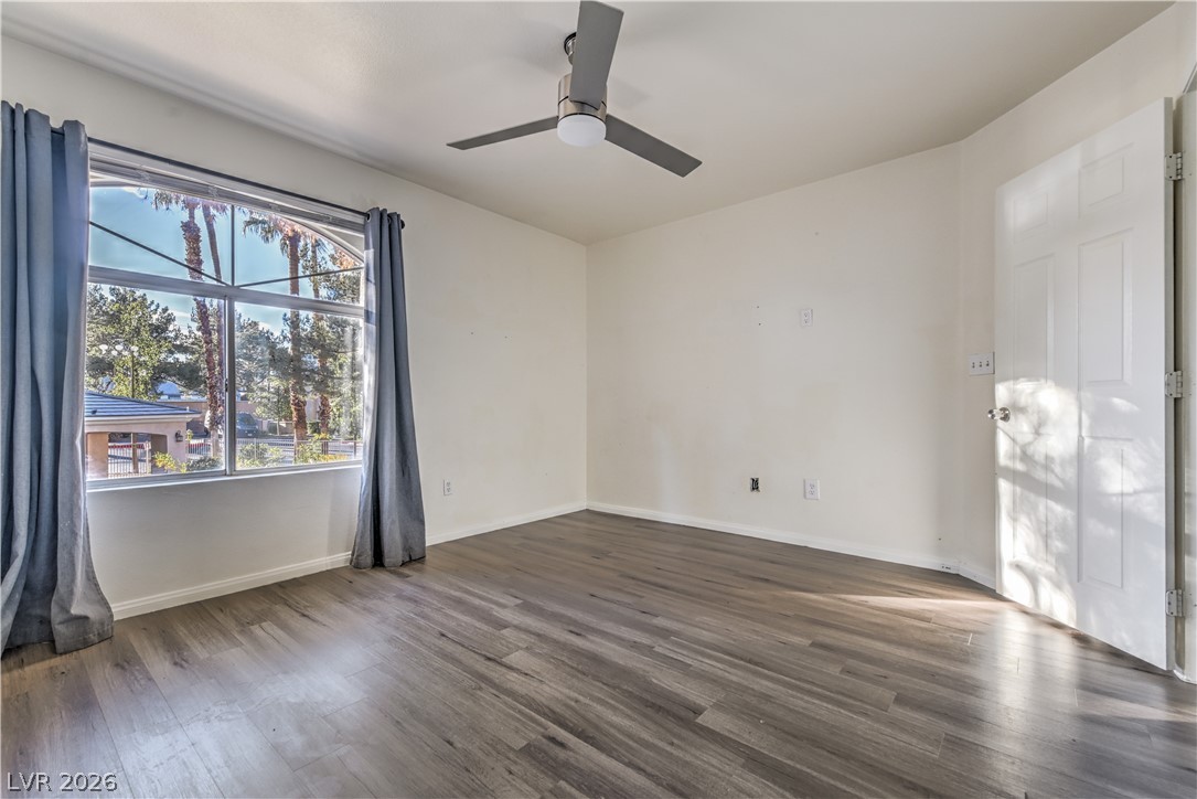 3950 South Sandhill Road, Unit 112 Las Vegas, NV 89121 - Photo 17 of 33 Unfurnished room with baseboards, wood finished floors, and a ceiling fan