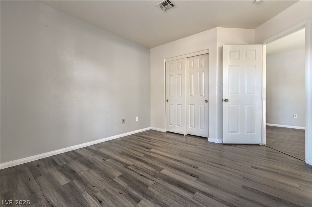 3950 South Sandhill Road, Unit 112 Las Vegas, NV 89121 - Photo 23 of 33 Unfurnished bedroom with baseboards, dark wood-style flooring, visible vents, and a closet