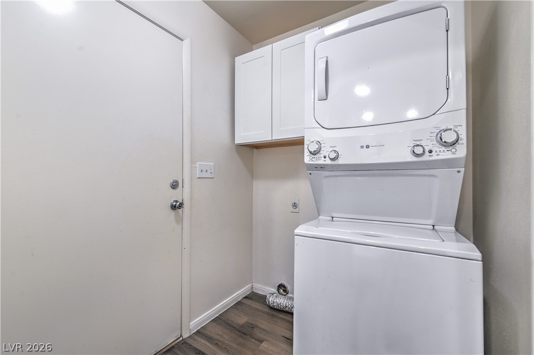 3950 South Sandhill Road, Unit 112 Las Vegas, NV 89121 - Photo 25 of 33 Washroom featuring dark wood-style floors, cabinet space, stacked washer / dryer, and baseboards