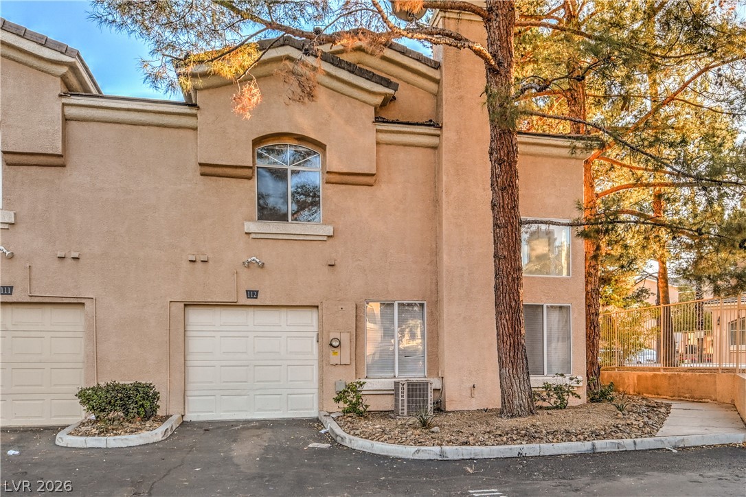 3950 South Sandhill Road, Unit 112 Las Vegas, NV 89121 - Photo 31 of 33 View of front facade with cooling unit, a garage, stucco siding, and fence