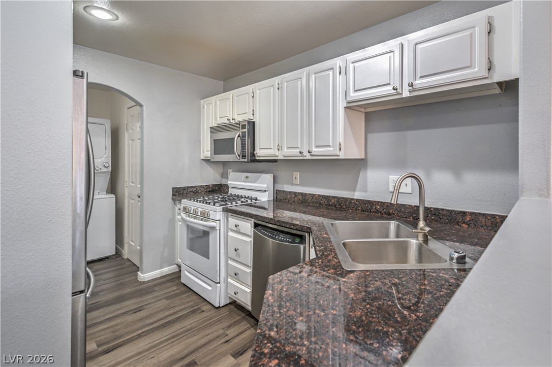 3950 South Sandhill Road, Unit 112 Las Vegas, NV 89121 - Photo 8 of 33 Kitchen featuring stainless steel appliances, arched walkways, white cabinetry, a sink, and dark wood-style floors