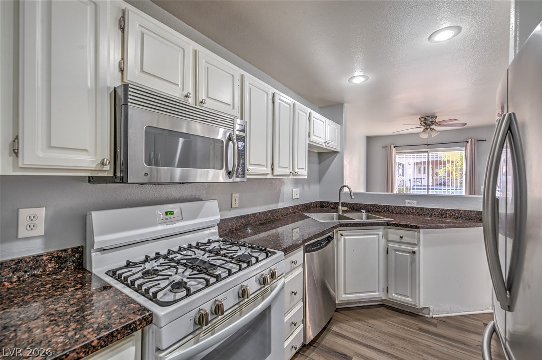 3950 South Sandhill Road, Unit 112 Las Vegas, NV 89121 - Photo 10 of 33 Kitchen featuring light wood-style flooring, a sink, white cabinets, a ceiling fan, and appliances with stainless steel finishes