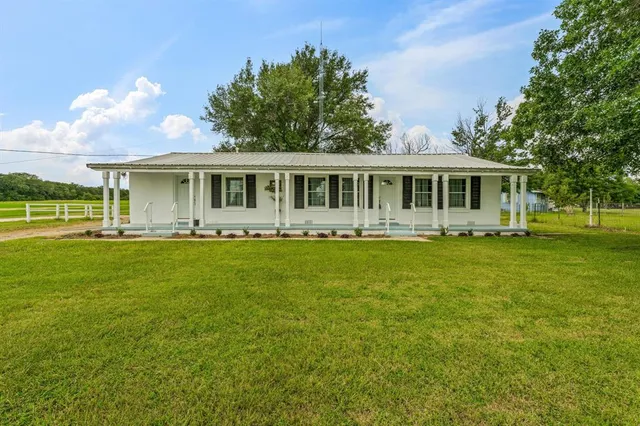 a front view of a house with a garden and lake view