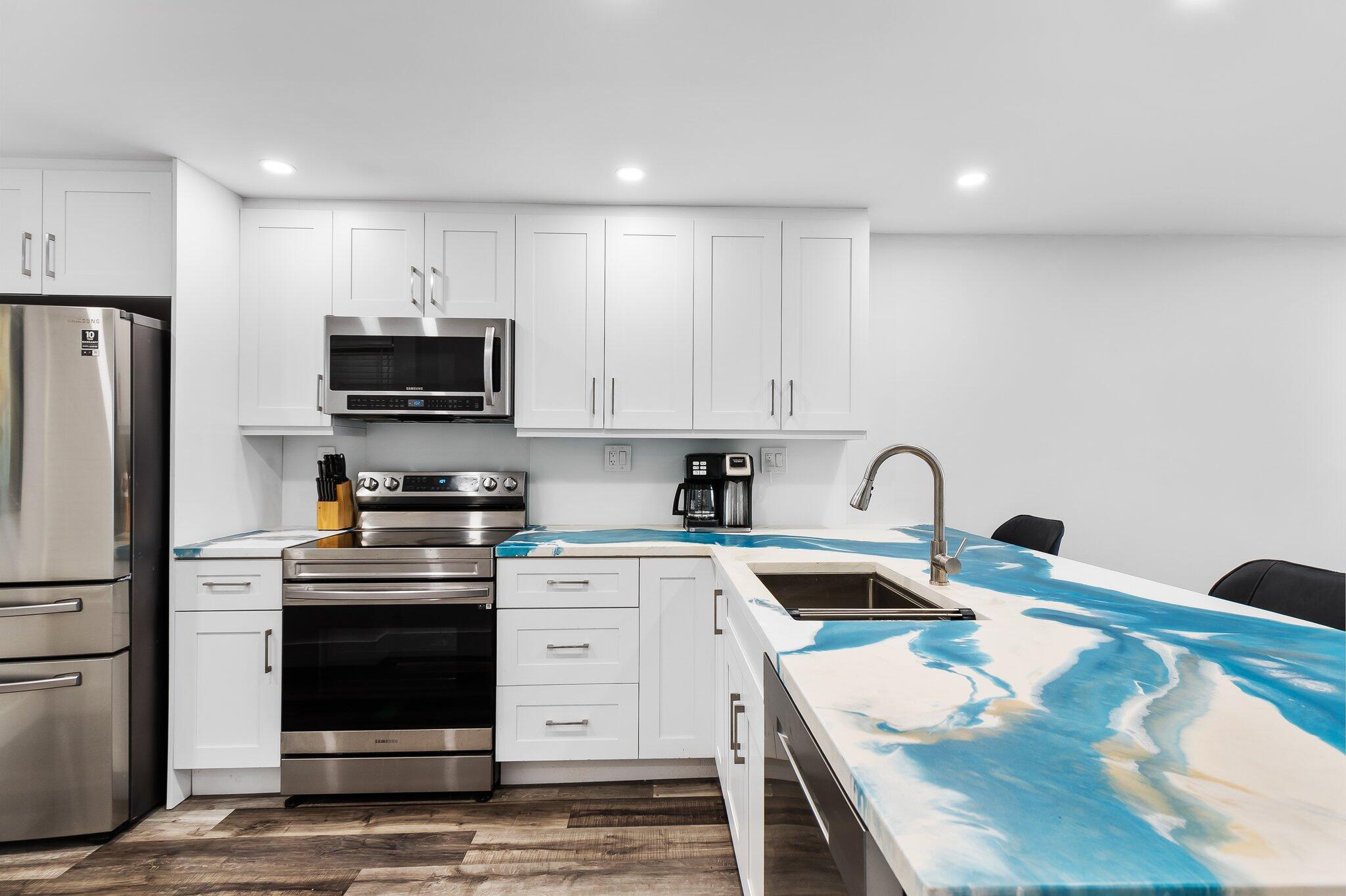 6 Royal Palm Way, Unit 509 Boca Raton, FL 33432 - Photo 4 of 23 a kitchen with kitchen island white cabinets stainless steel appliances and sink