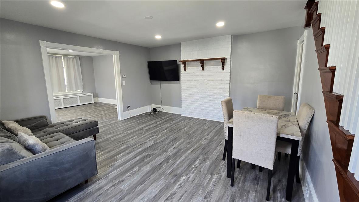 883 North Locust Street Hazleton, PA 18201 - Photo 15 of 83 Laminate flooring connects the open-plan living and dining areas, anchored by a white brick accent wall.
