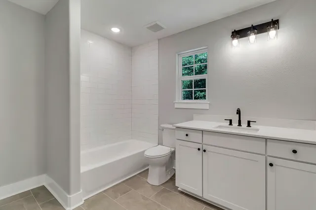 a bathroom with a bathtub sink mirror and toilet