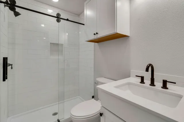 a bathroom with a sink a toilet and shower