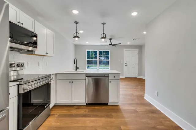 a large kitchen with stainless steel appliances granite countertop a stove and a sink