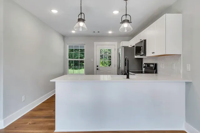 a view of kitchen with stainless steel appliances granite countertop a refrigerator a stove a sink and a window