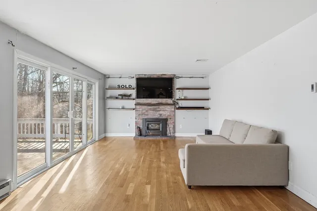 a living room with furniture a fireplace and a flat tv screen next to a window