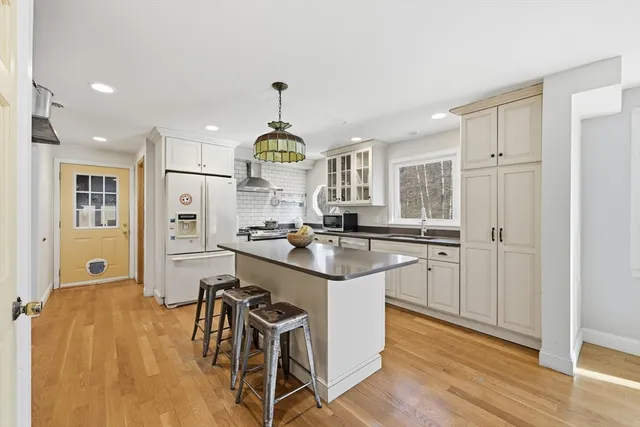 a kitchen with stainless steel appliances a dining table chairs and wooden floor