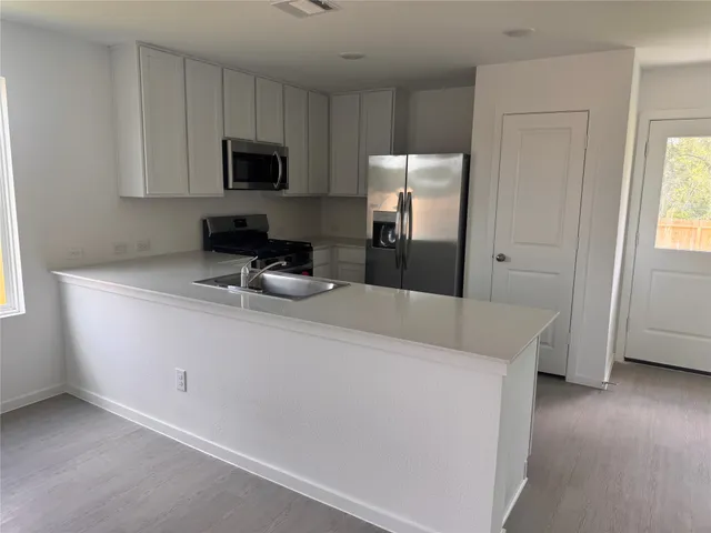 a kitchen with stainless steel appliances a refrigerator sink and microwave