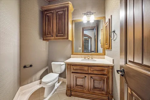 a bathroom with a granite countertop toilet a sink and a mirror