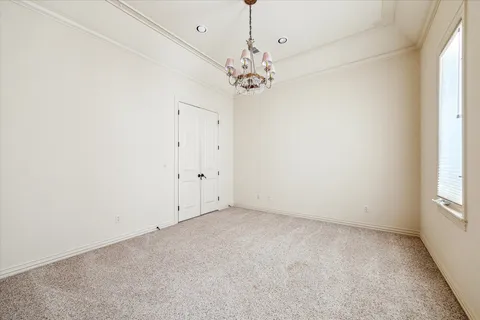 an empty room with a chandelier fan and windows