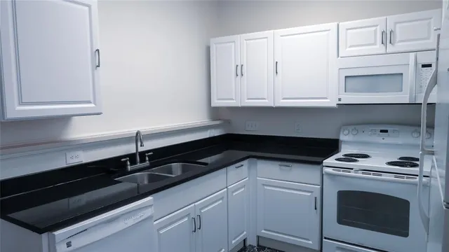 a kitchen with white cabinets and black appliances