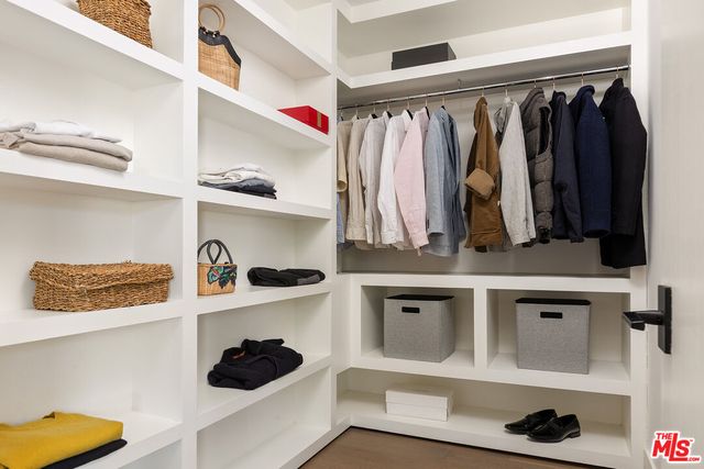 a view of walk in closet with clothes and shoes