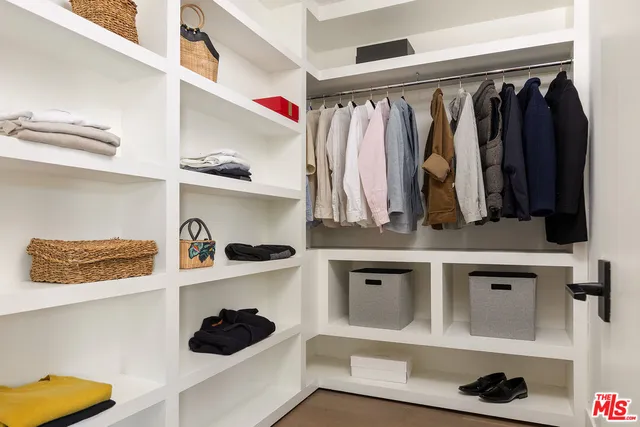 a view of walk in closet with clothes and shoes