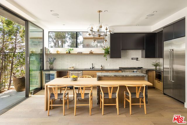 a kitchen with stainless steel appliances granite countertop a stove top oven a sink a dining table and chairs