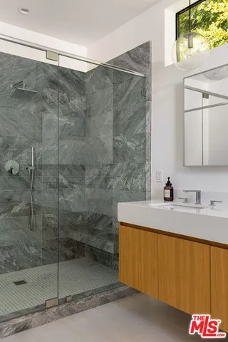 a bathroom with a granite countertop sink a mirror and shower