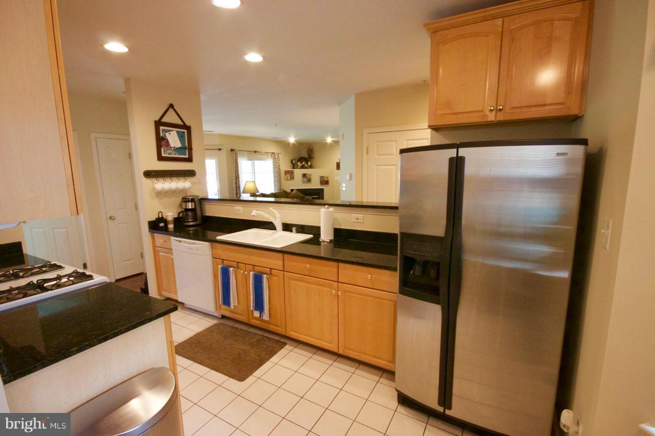 25252 Riffleford Square, Unit 101 Chantilly, VA 20152 - Photo 9 of 30 a kitchen with stainless steel appliances granite countertop a refrigerator a stove and a sink with wooden floor