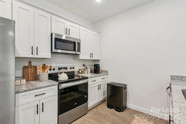 a kitchen with granite countertop white cabinets sink and stainless steel appliances