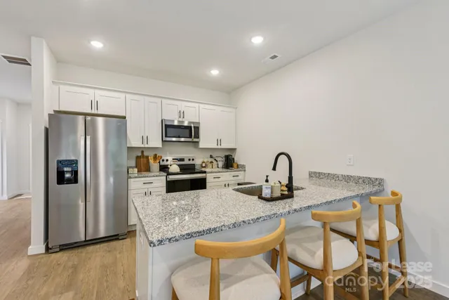 a kitchen with granite countertop a refrigerator and a stove top oven