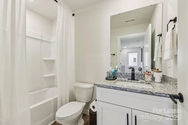 a bathroom with a granite countertop sink mirror vanity and toilet