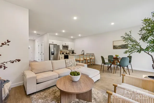 a living room with furniture and a dining table with wooden floor