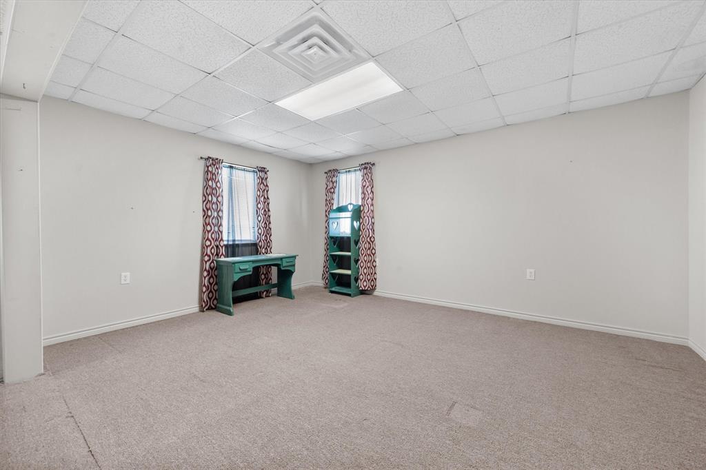 2101 Ridge View Drive Cleburne, TX 76033 - Photo 19 of 31 Spacious room featuring neutral carpeting, light gray walls, and a drop-ceiling with integrated lighting