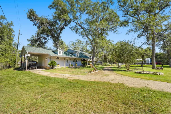 a view of a house with a big yard and large trees