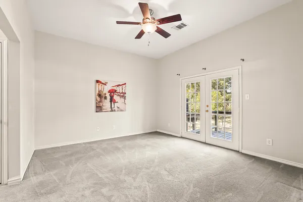 an empty room with windows and fan