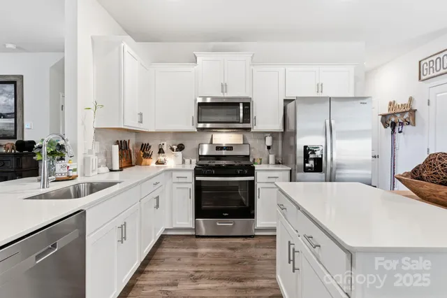 a kitchen with white cabinets and stainless steel appliances