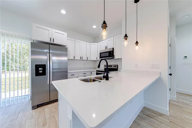 a kitchen with kitchen island a counter space a sink appliances and wooden floor
