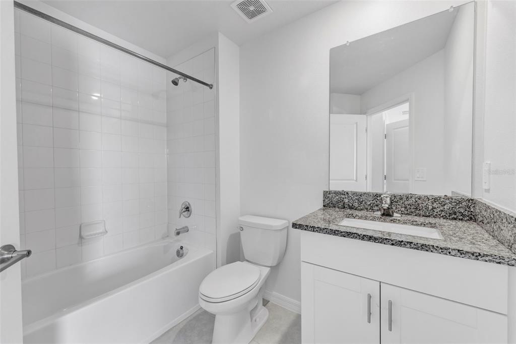 8309 Corner Pine Way New Port Richey, FL 34655 - Photo 22 of 33 a bathroom with a granite countertop sink toilet mirror and bathtub