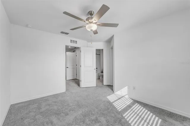 an empty room with a window and a ceiling fan