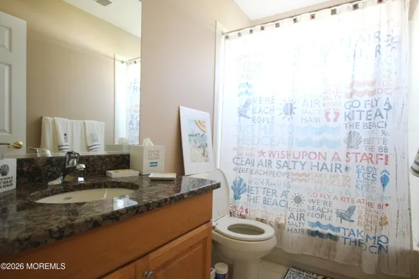 a bathroom with a granite countertop sink a toilet and shower