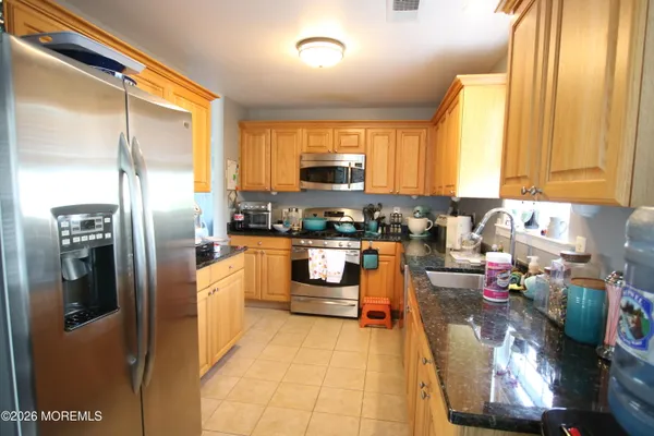 a kitchen with stainless steel appliances granite countertop a refrigerator a stove and a sink