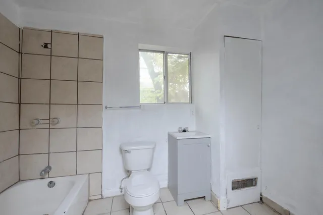 a white toilet sitting next to a bath tub and vanity