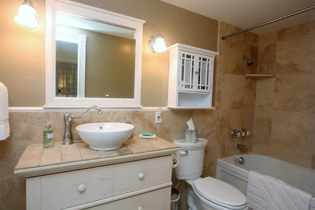 a bathroom with a granite countertop sink toilet a mirror a bathtub and shower