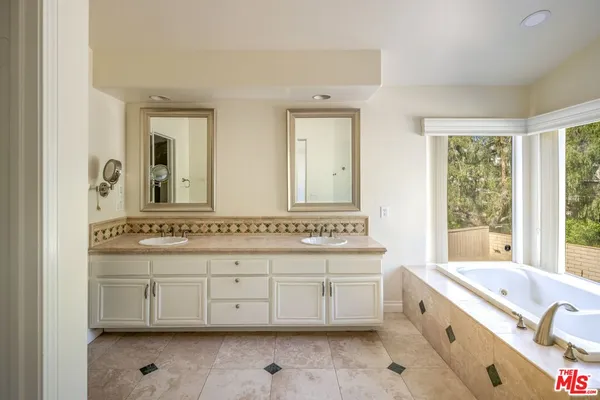 a bathroom with a granite countertop double vanity sink a mirror and a bathtub