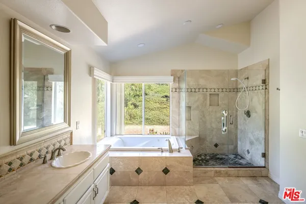 a bathroom with a tub sink and mirror