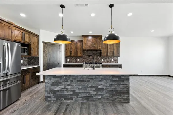 a kitchen with kitchen island a counter top space a sink appliances and cabinets