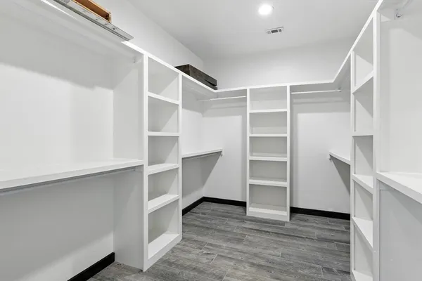 a room with walk in closet and wooden floor